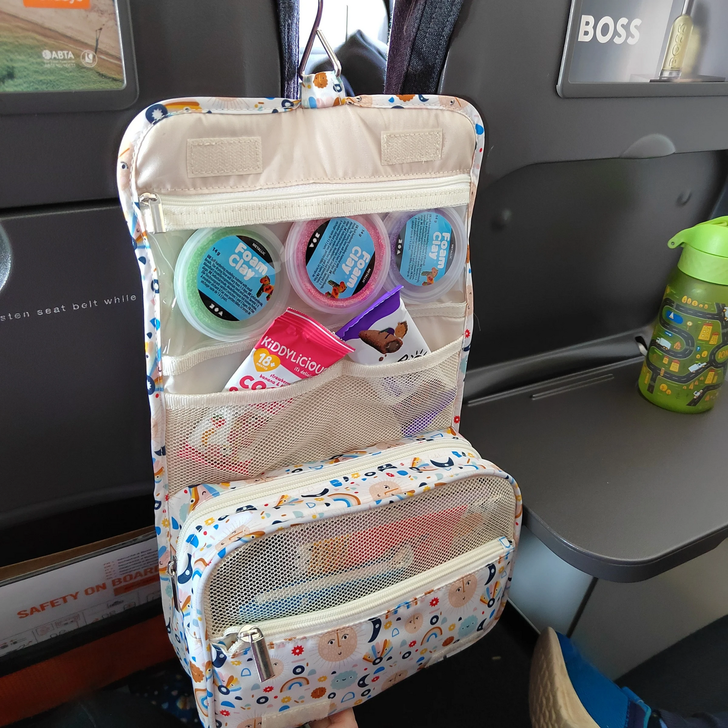 Children's toiletry bag with various items and toys on a car seat