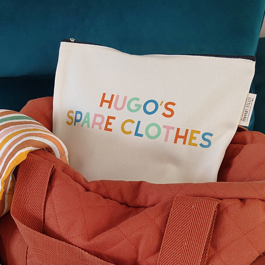 Canvas pouch with 'HUGO'S SPARE CLOTHES' text in colorful letters on a red bag.